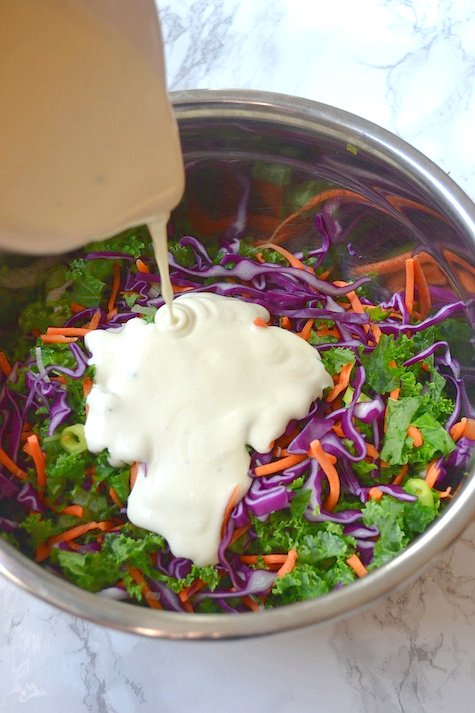pouring-creamy-greek-yogurt-dressing-on-kale-slaw